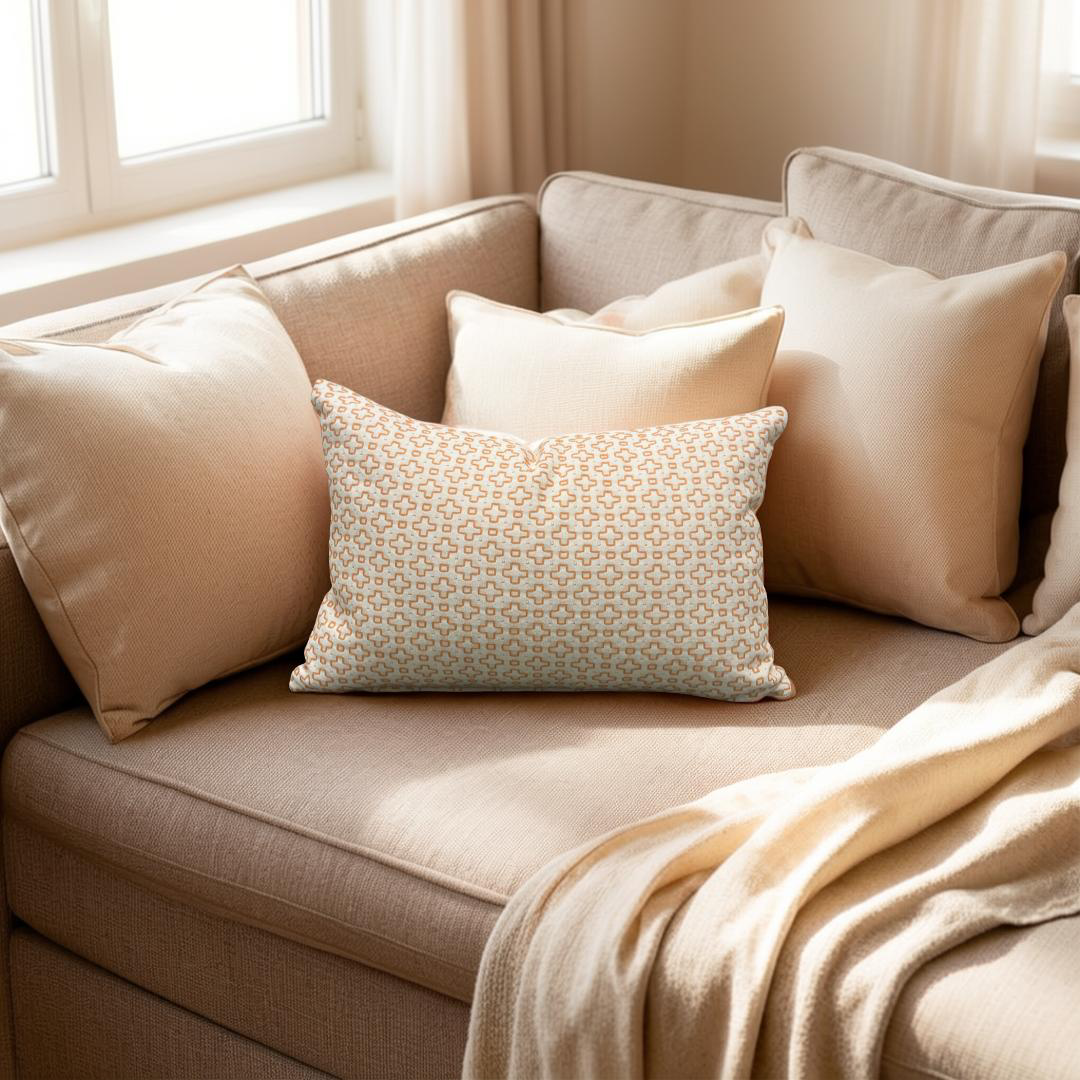 Beige sofa with patterned pillow and blanket in a cozy living room.