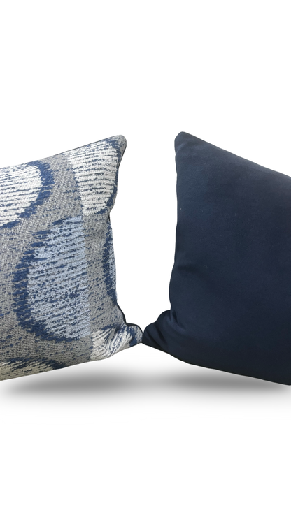 Two decorative pillows, one with a textured pattern and the other solid black, on a white background.
