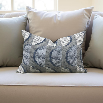 Decorative pillow with a blue and gray pattern on a beige sofa.