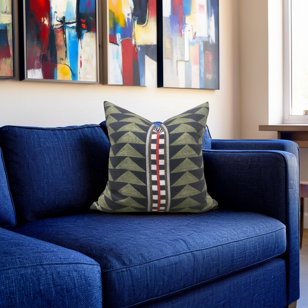 Blue sofa with a patterned pillow in a room with abstract paintings on the wall.