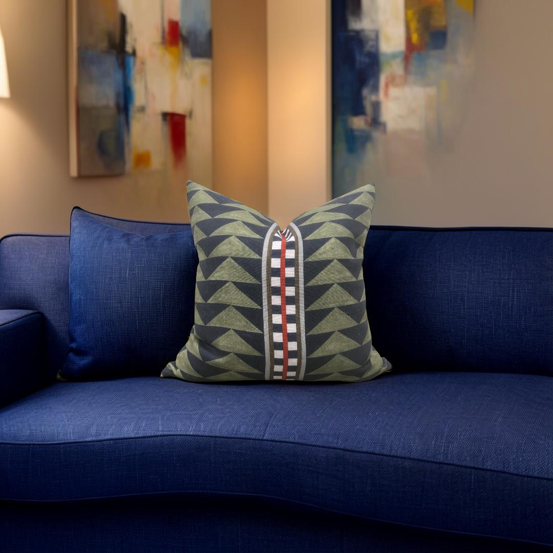 Decorative pillow with geometric pattern on a blue couch in a room with abstract art on the wall.
