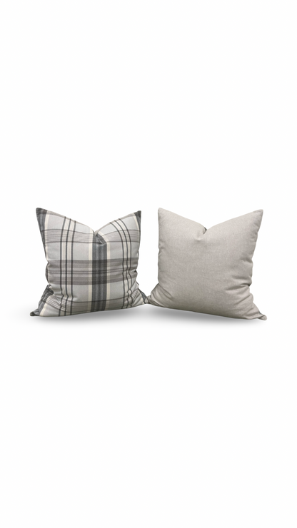 Two pillows, one plaid and one solid, on a white background