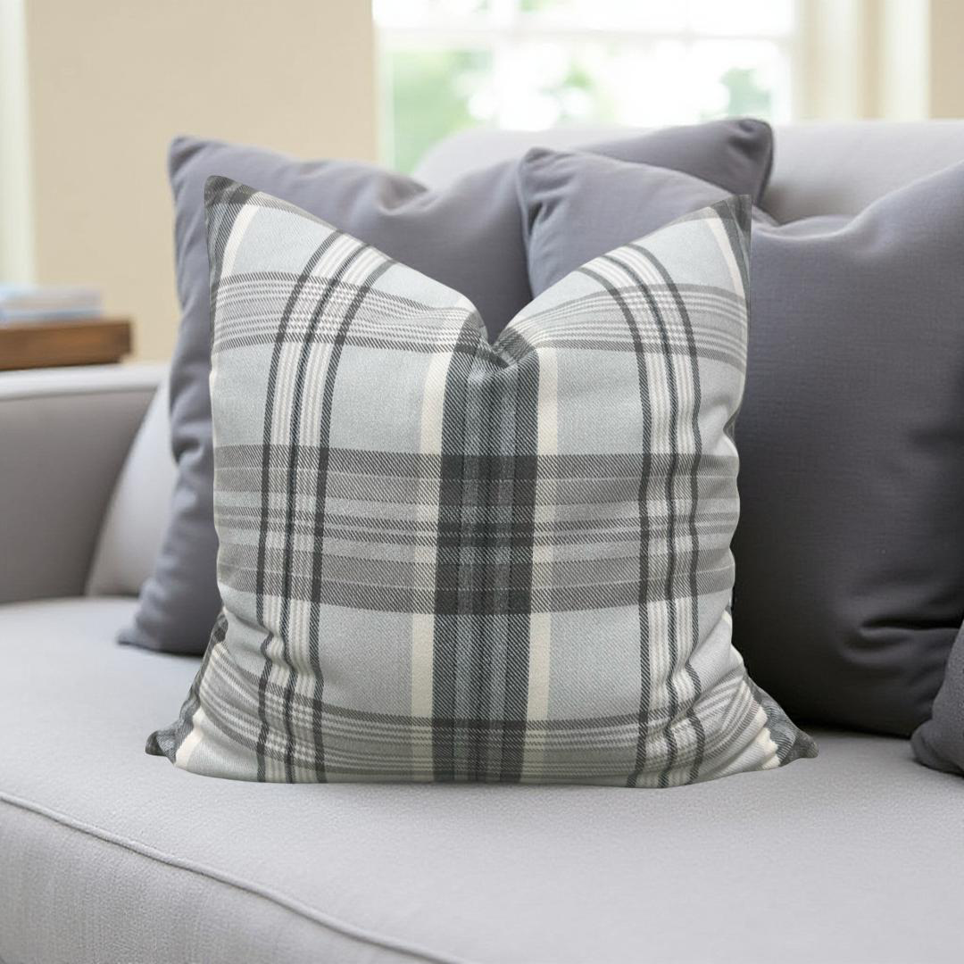 Plaid pillow on a gray sofa with a neutral background