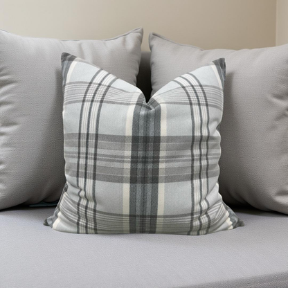 Plaid pillow on a gray sofa with other pillows in the background