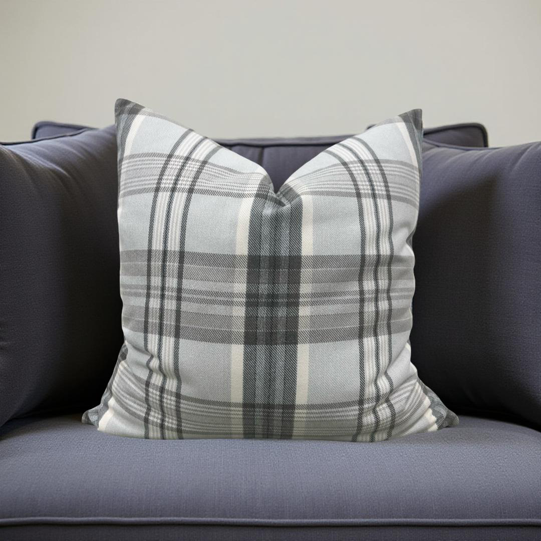 Plaid pillow on a gray sofa against a neutral background