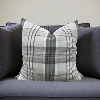 Plaid pillow on a gray sofa against a neutral background