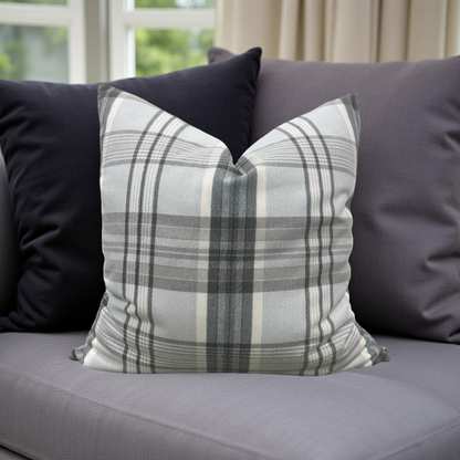 Plaid pillow on a gray sofa with a blurred window background