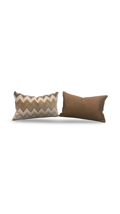 Two pillows, one with a zigzag pattern and the other solid brown, on a white background.