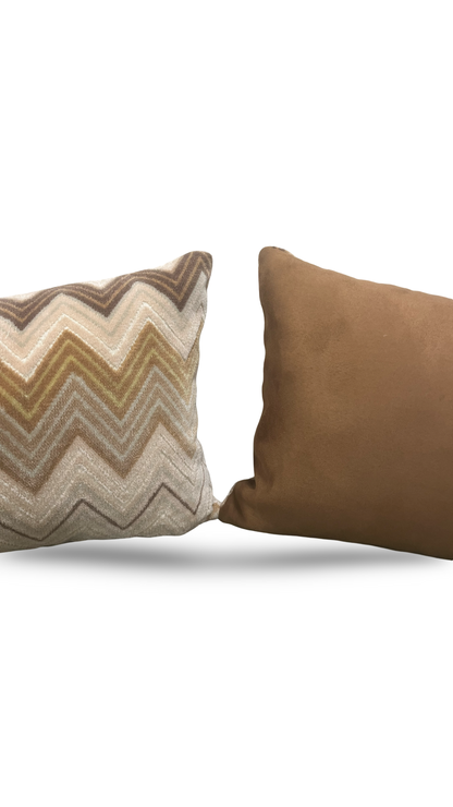 Two pillows, one with a zigzag pattern and the other solid brown, on a white background.
