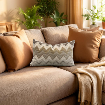 Beige sofa with patterned pillow and blanket in a cozy living room setting