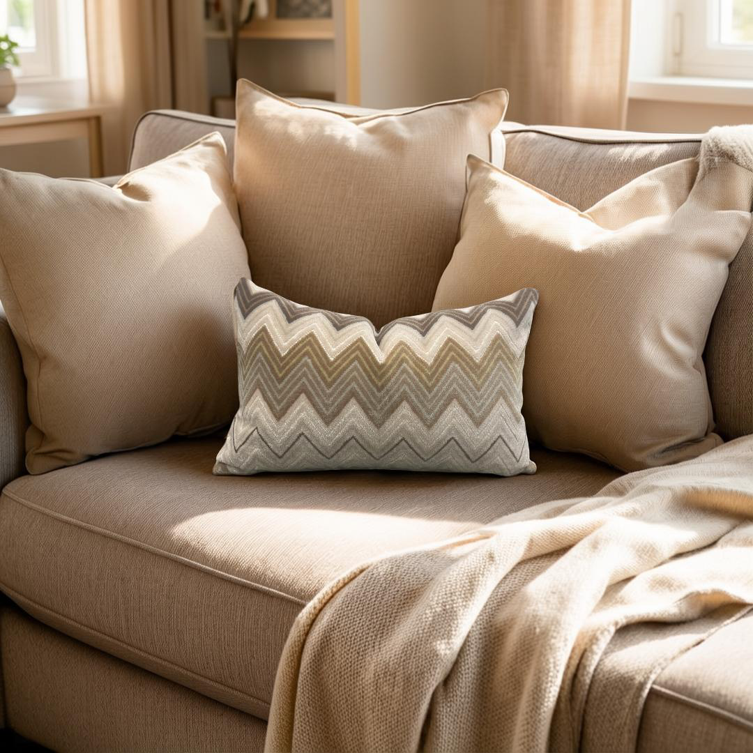 Beige sofa with patterned pillow and blanket in a cozy living room.