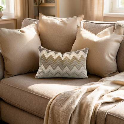 Beige sofa with patterned pillow and blanket in a cozy living room.