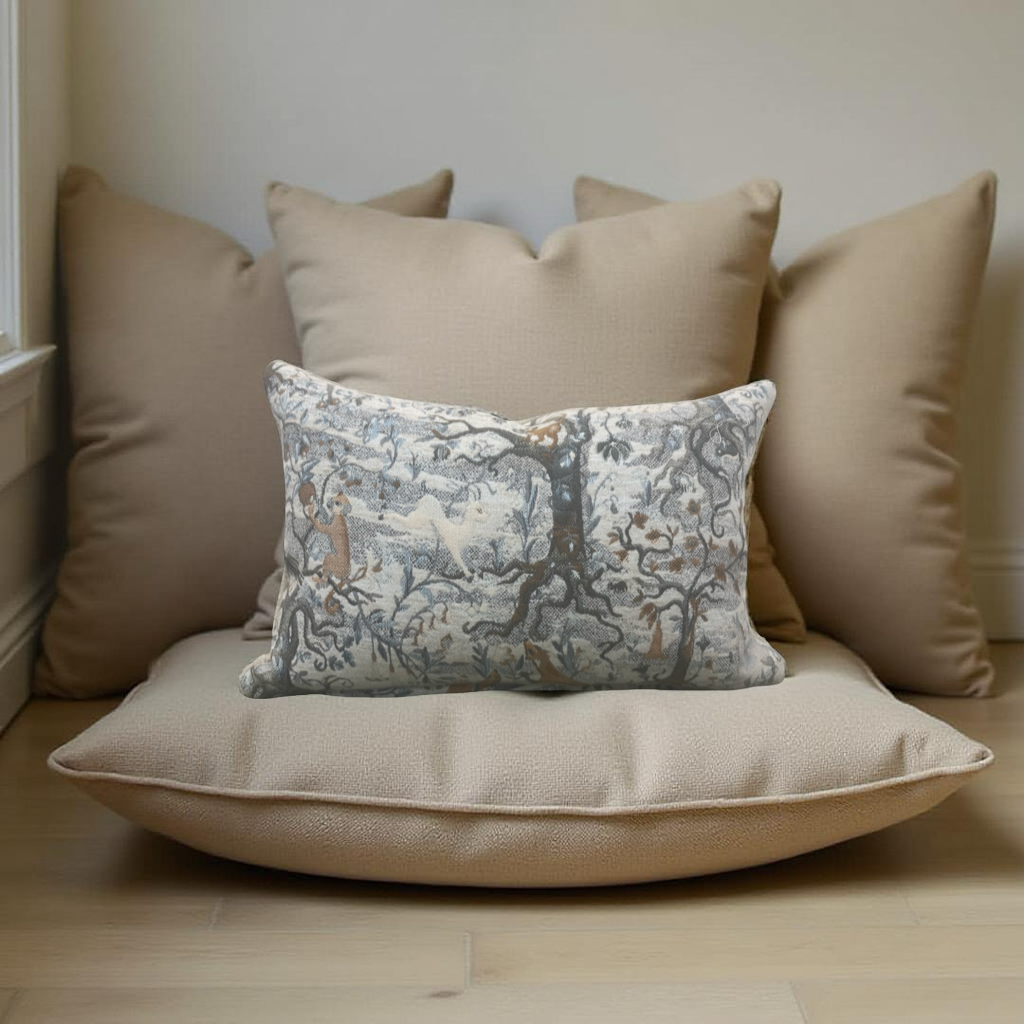 Decorative pillow with intricate pattern on a beige cushion, surrounded by plain pillows against a neutral wall.