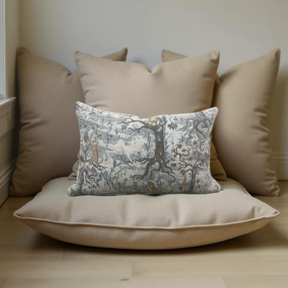 Decorative pillow with intricate pattern on a beige cushion, surrounded by plain pillows against a neutral wall.