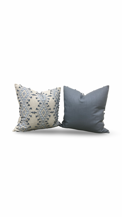 Two decorative pillows, one with a geometric pattern and the other solid color, on a white background.