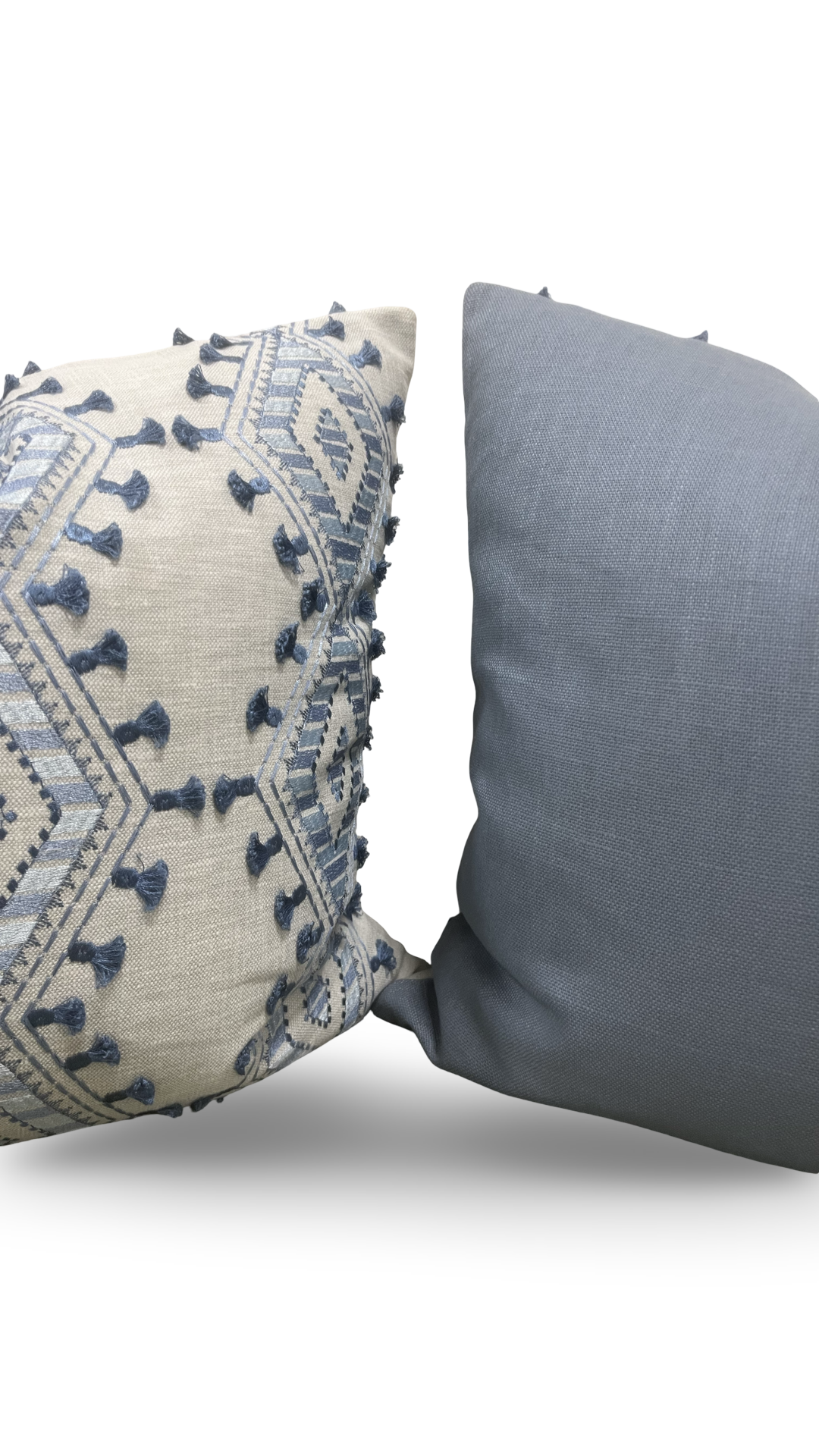 Two pillows, one with intricate blue patterns on a beige background and the other plain gray, on a white background.