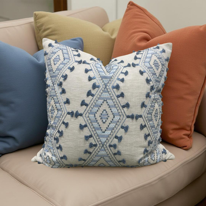 Decorative pillow with geometric pattern on a beige sofa with other colorful pillows.