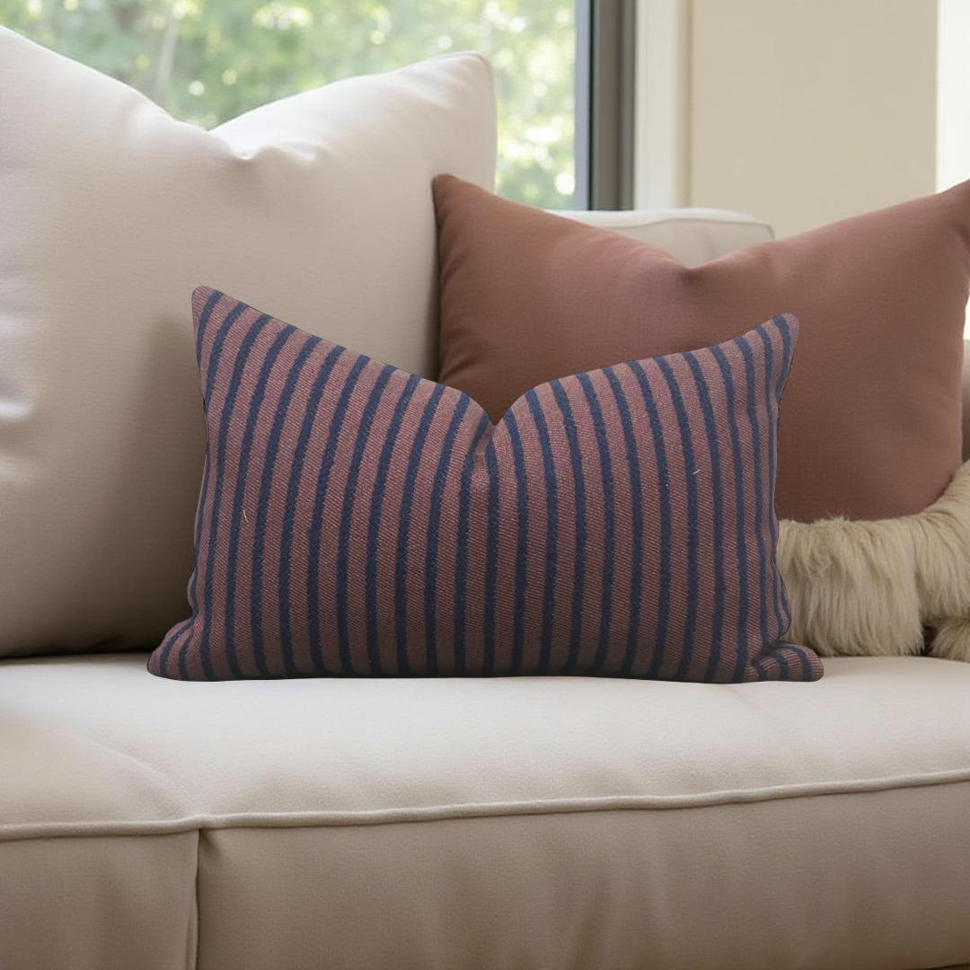 Striped pillow on a beige sofa with a blurred window background