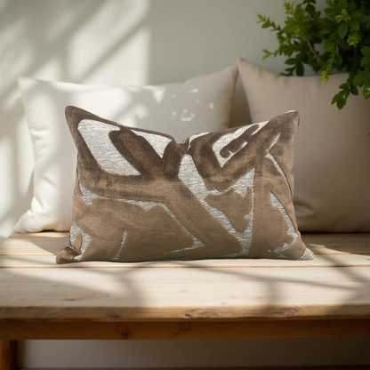 Decorative pillow with geometric pattern on a wooden bench with a plant in the background