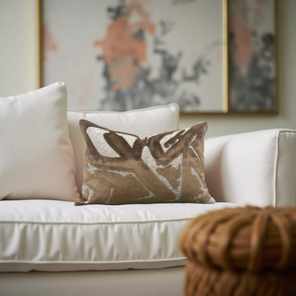 White sofa with patterned brown pillow and abstract art in the background