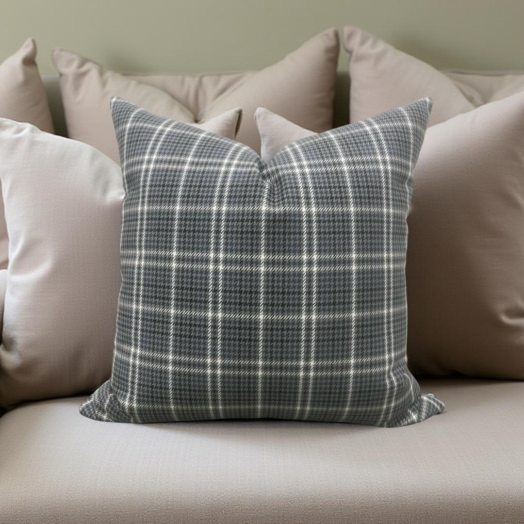 Plaid pillow on a beige sofa with other pillows in the background