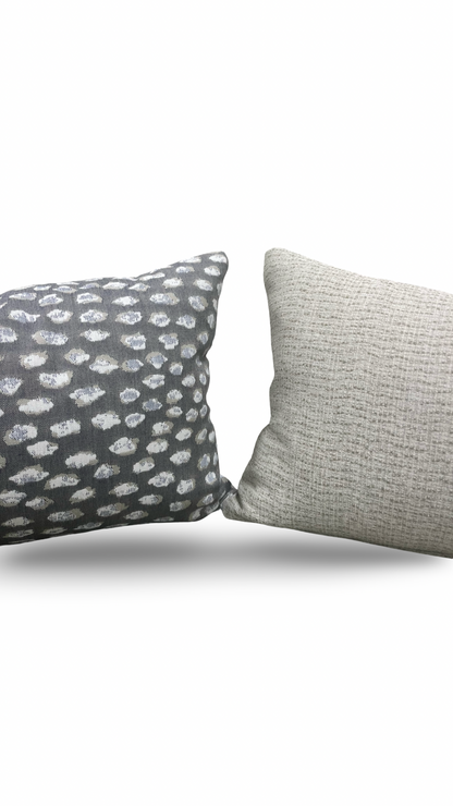 Two textured pillows, one with a pattern and one solid color, on a white background.
