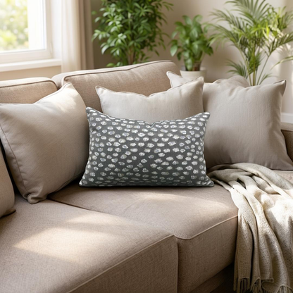 Beige sofa with decorative pillows and a blanket in a cozy living room setting.