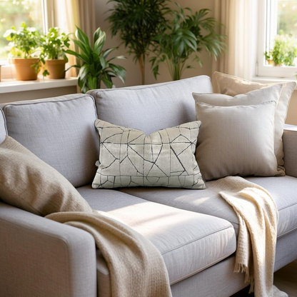 Gray sofa with decorative pillows and a blanket in a bright living room with plants.