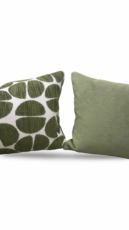 Two green pillows, one with a leaf pattern, on a white background