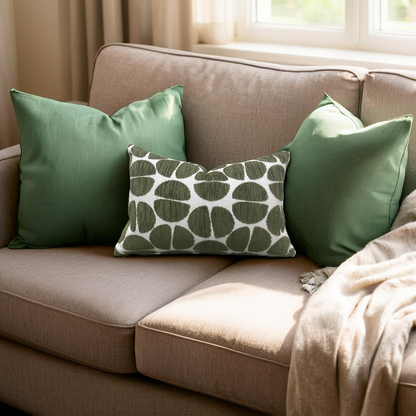 Beige sofa with green pillows and a patterned pillow in a cozy living room setting.