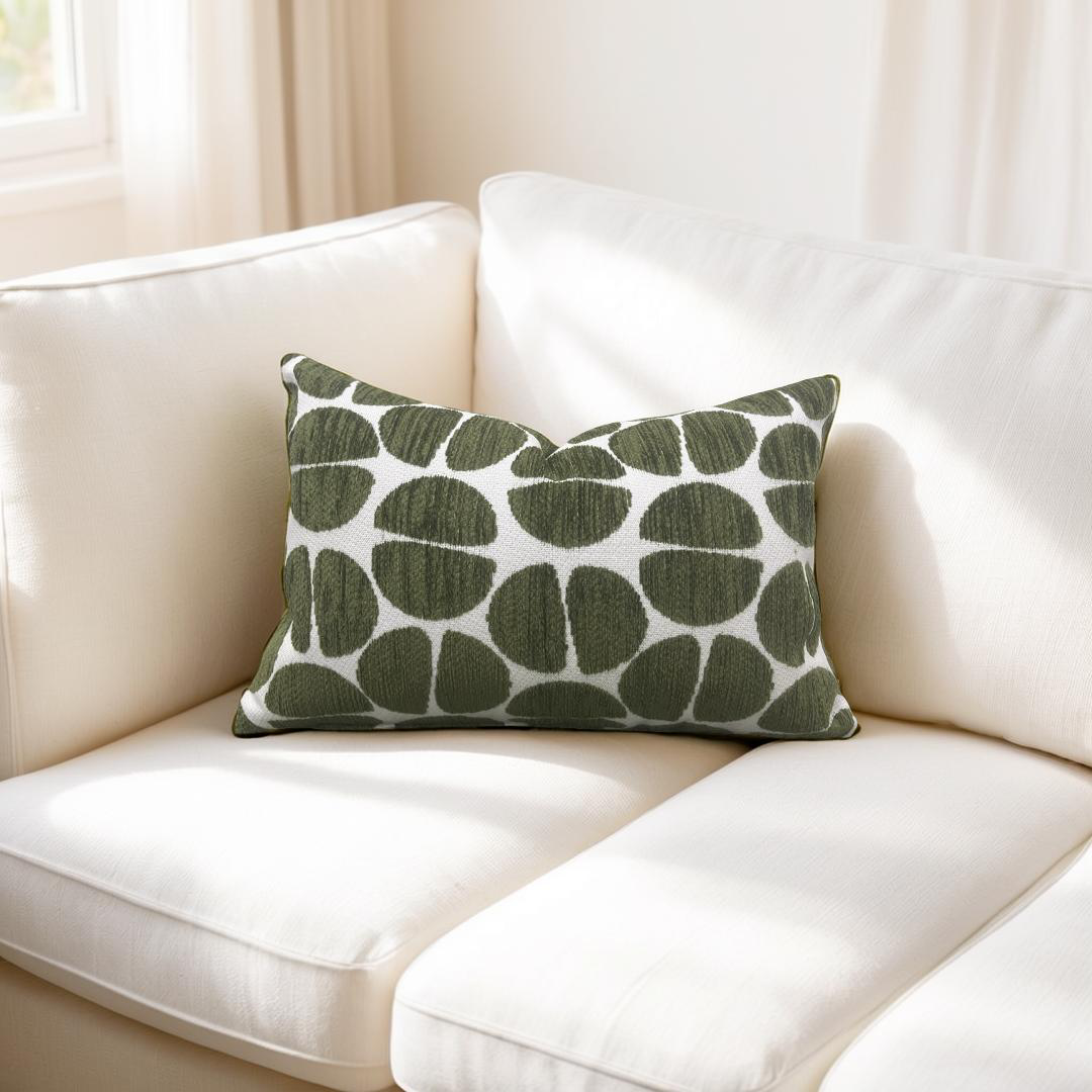 Green patterned pillow on a white couch with a neutral background