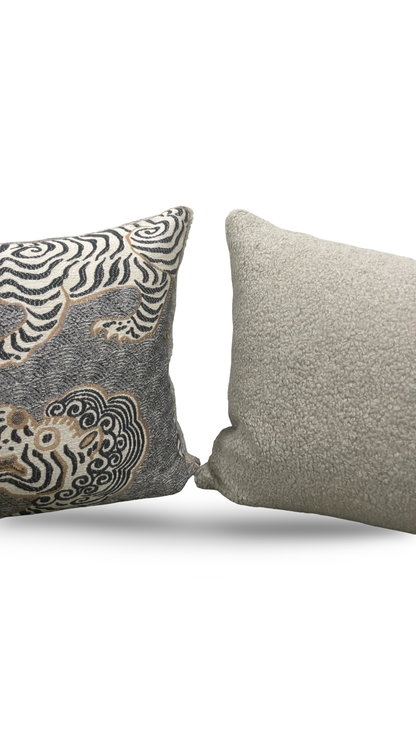 Two decorative pillows, one with a zebra pattern and the other plain gray, on a white background.
