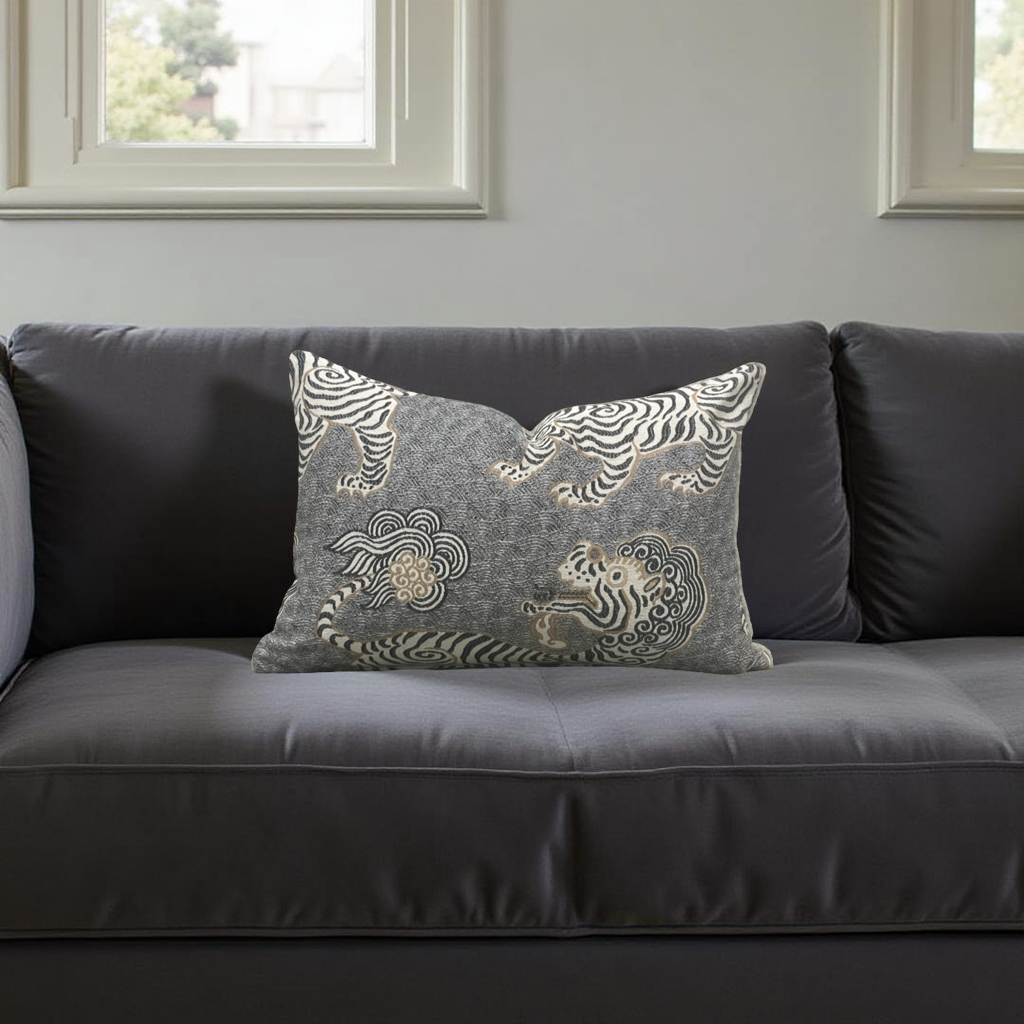 Gray sofa with decorative pillow featuring tiger design in a room with windows.