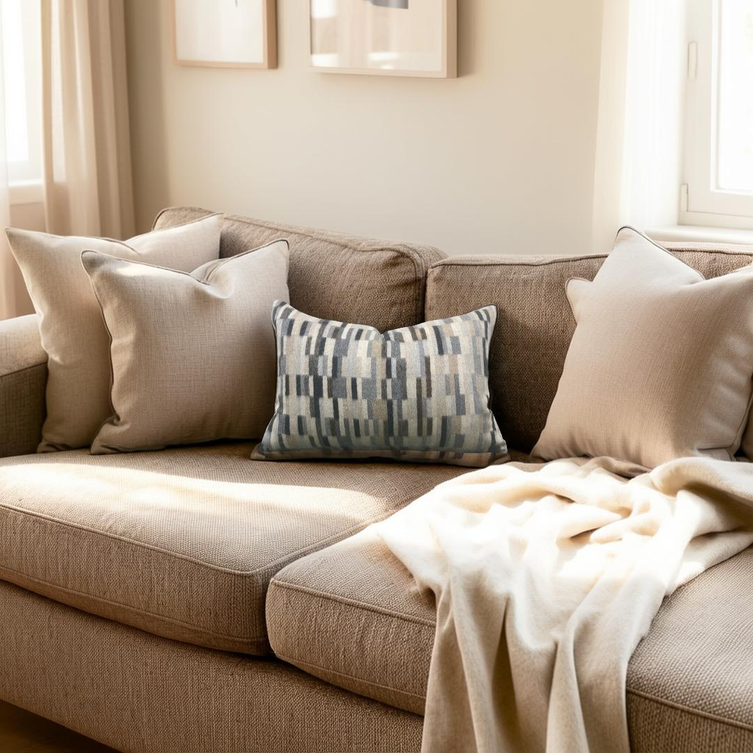 Brown sofa with decorative pillows and a blanket in a cozy living room.