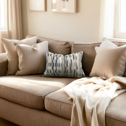 Brown sofa with decorative pillows and a blanket in a cozy living room.