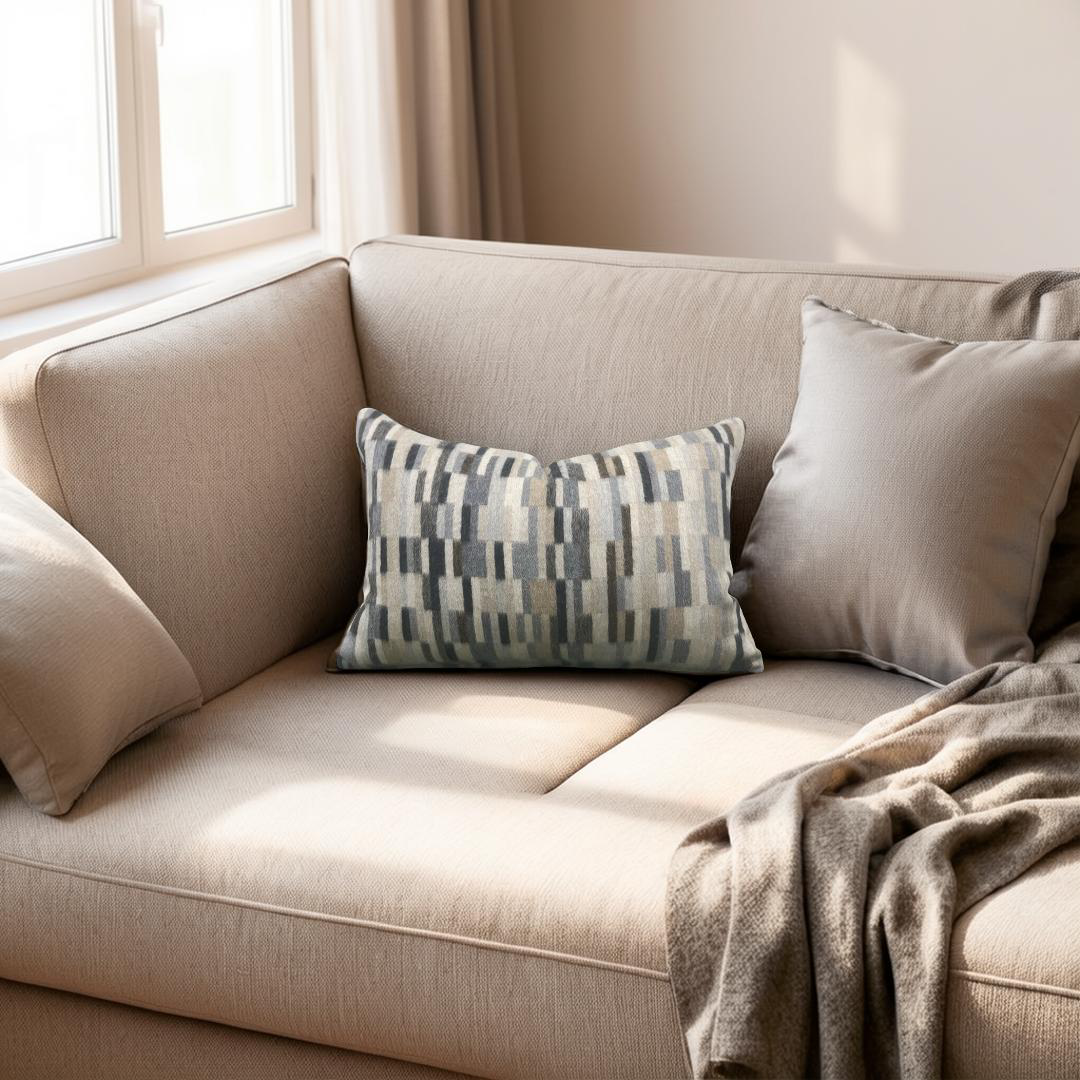 Beige sofa with patterned pillow and blanket in a bright room