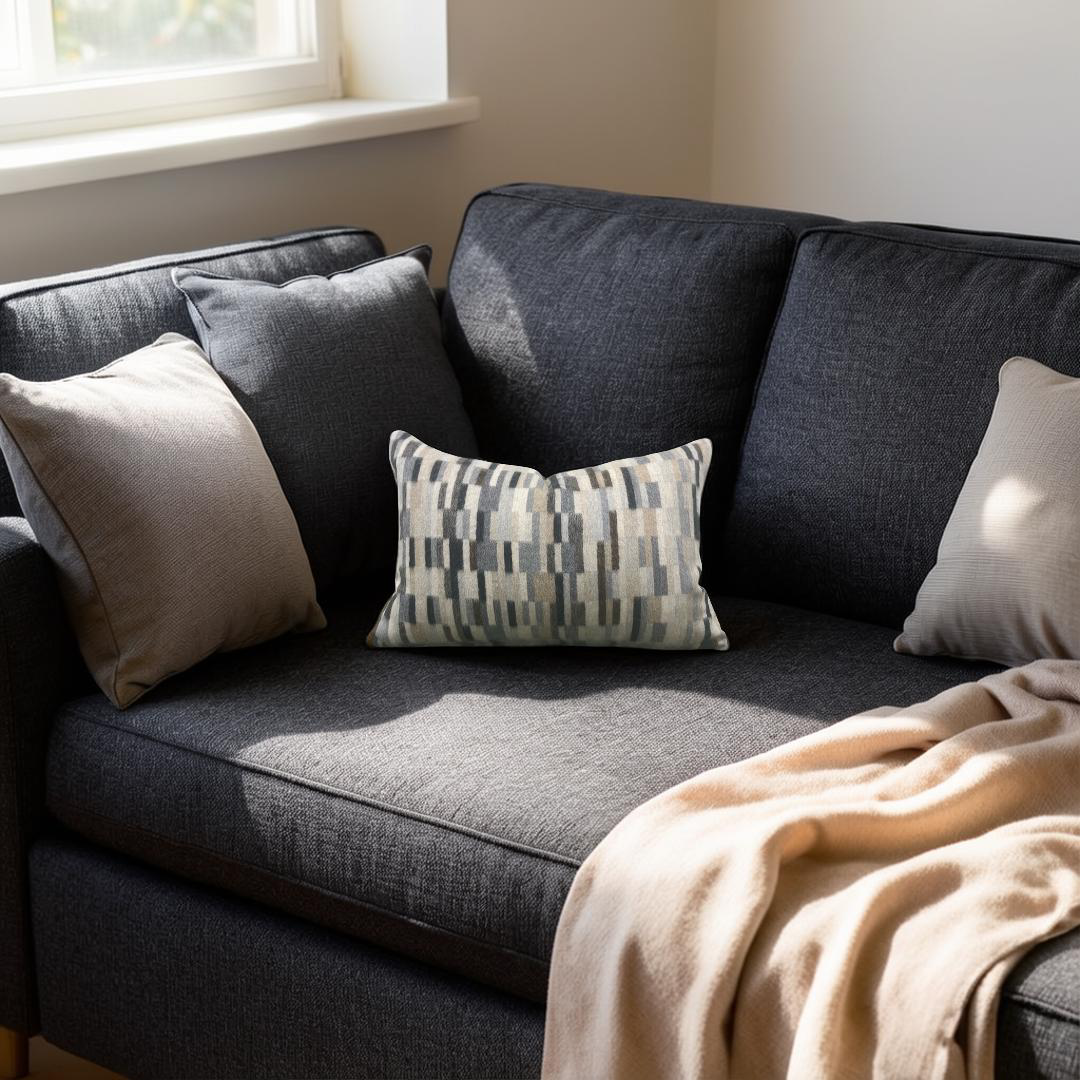 Gray sofa with cushions and a blanket in a room with a window.