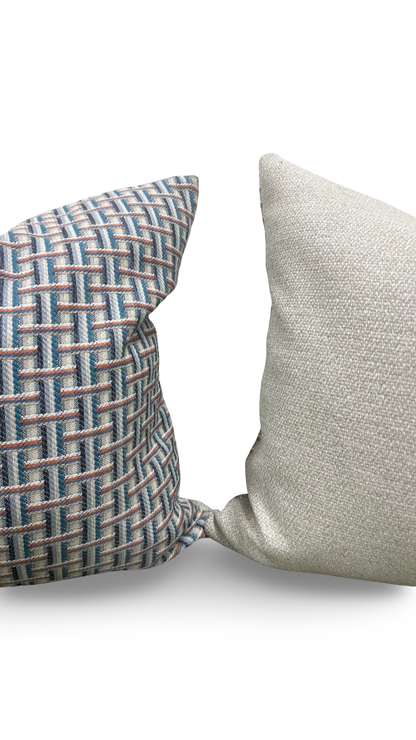 Two textured pillows, one with a geometric pattern and the other plain, on a light background.