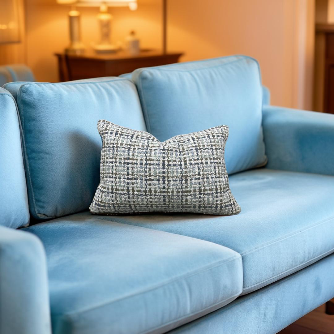 Light blue sofa with a textured gray pillow in a softly blurred room setting