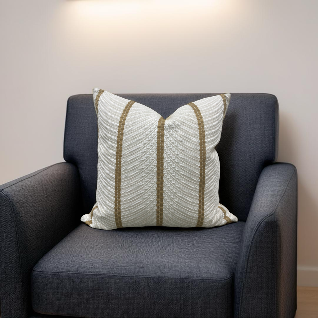 Gray armchair with a decorative pillow featuring white and brown stripes against a plain wall.