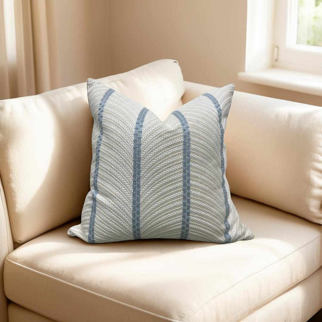 Blue patterned pillow on a beige sofa with a neutral background