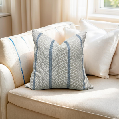 Decorative pillow with blue stripes on a beige sofa in a bright room.