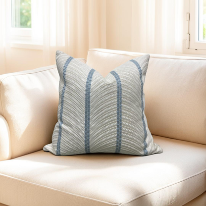 Decorative pillow with blue stripes on a beige sofa in a bright room.