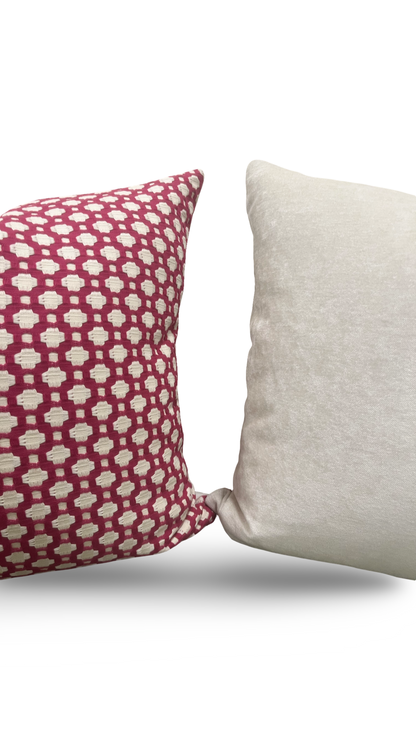 Two pillows, one with a red and white pattern and the other plain beige, on a white background.
