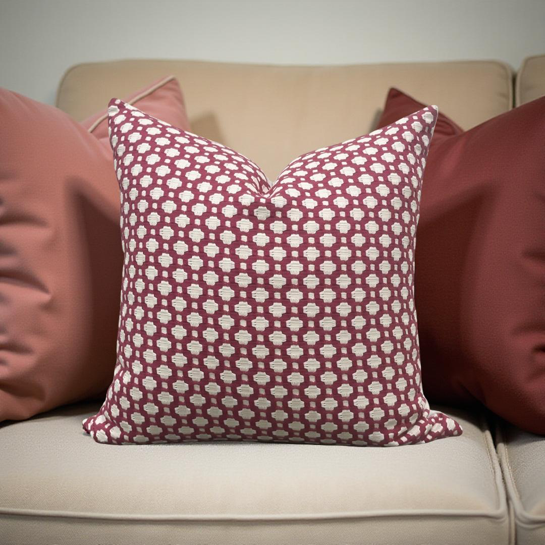 Patterned red and white pillow on a beige sofa with other pillows.