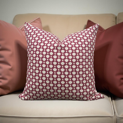 Patterned red and white pillow on a beige sofa with other pillows.