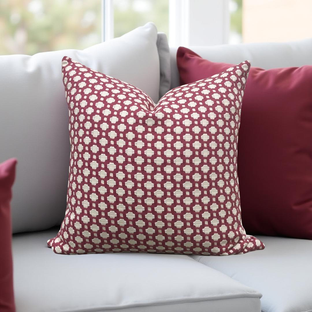 Red patterned pillow on a white sofa with a blurred window background