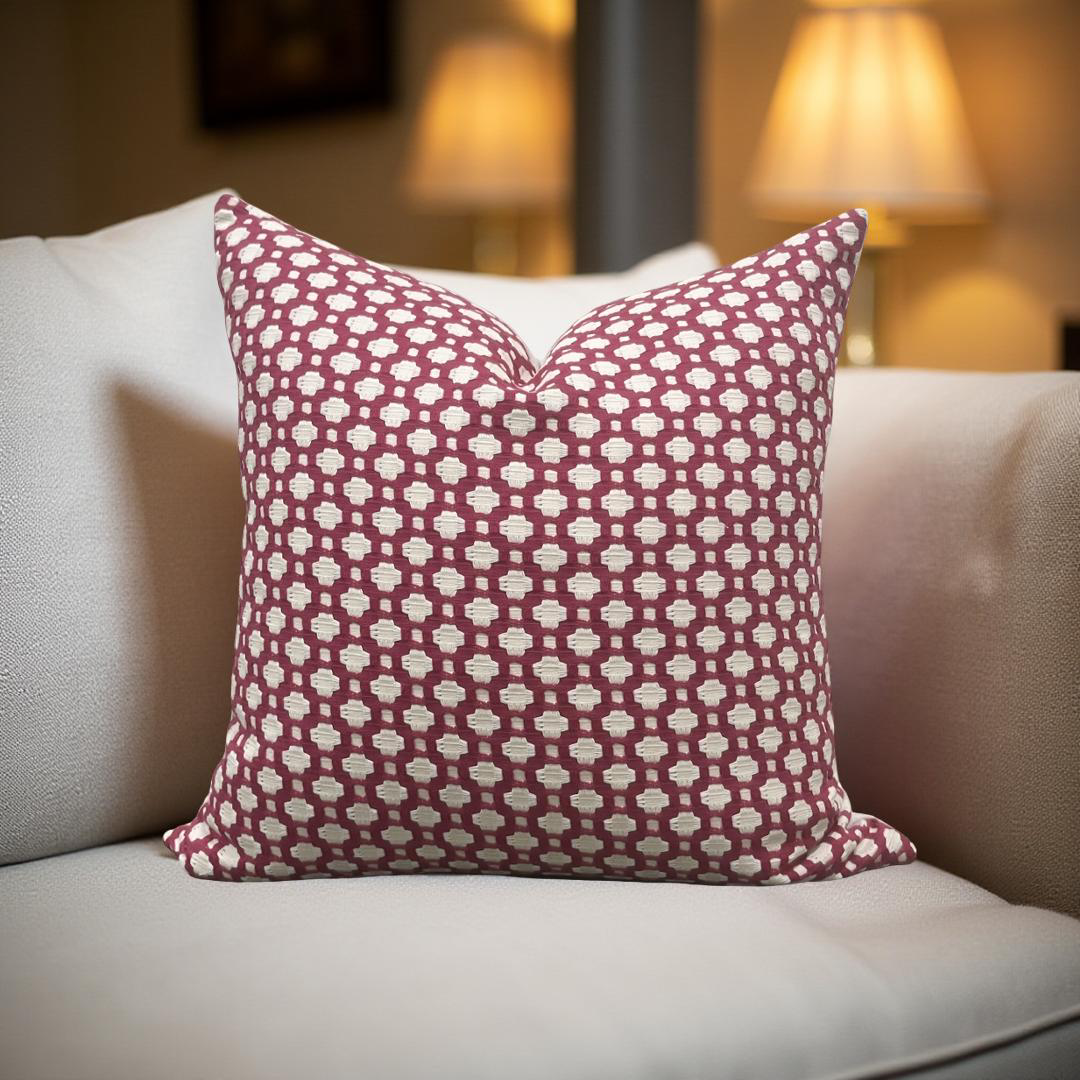 Patterned red and white pillow on a beige sofa with blurred lamps in the background